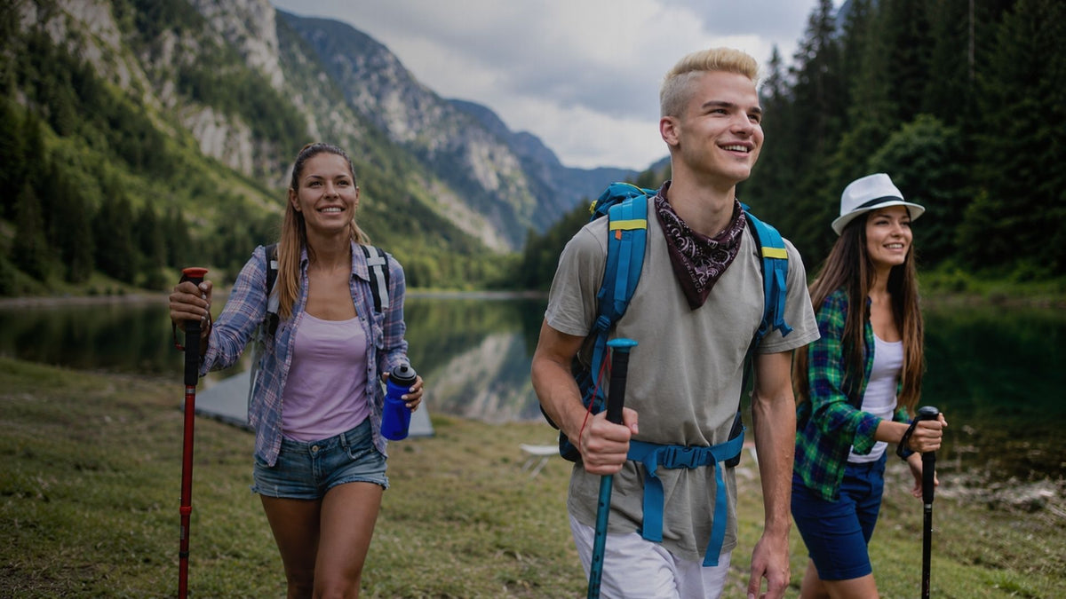 Three people hiking in a mountainous area with a lake in the background