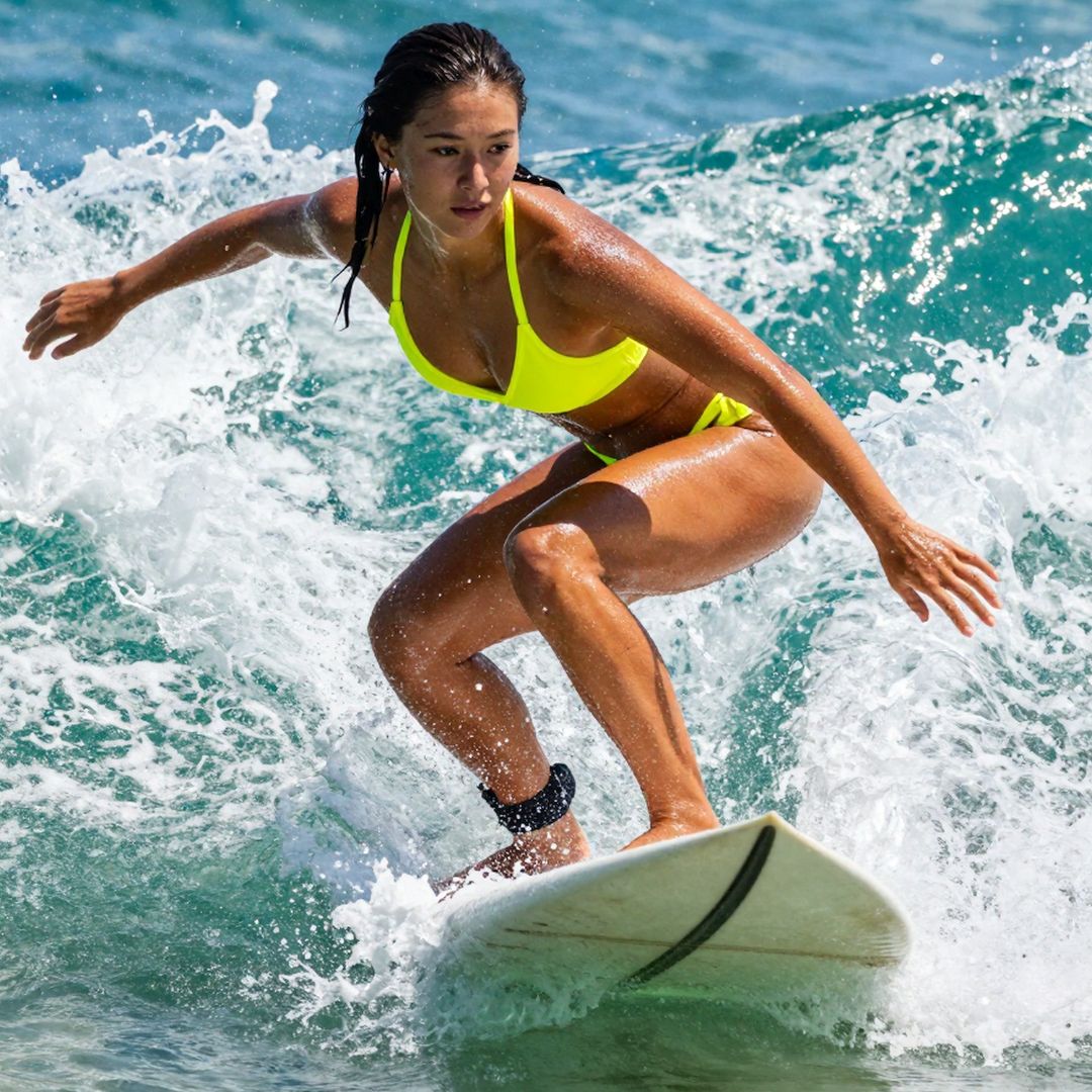 Woman surfing on a wave in a bright yellow bikini